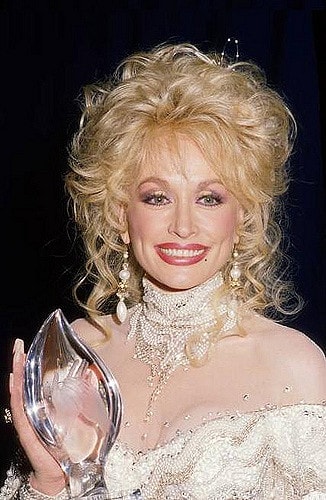 Dolly Parton, one of the richest artists of all time, holding a People's Choice Awards in 1988.